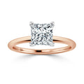 Rose gold ring with a square-cut diamond solitaire set in a four-prong white gold setting, shown on white background.