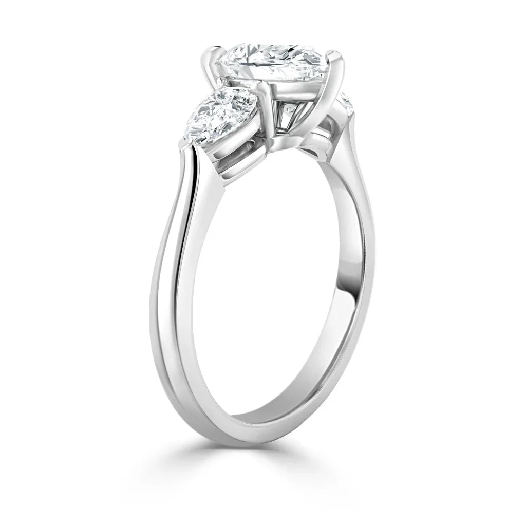 A three-stone diamond engagement ring with a sleek white gold band, shown from a side angle.
