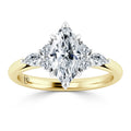 Gold band ring with a marquise-cut center diamond and four smaller side diamonds set in a symmetrical design.