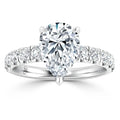 Pear-shaped diamond ring with a white gold band, accented by round diamonds along the shank, on white background.