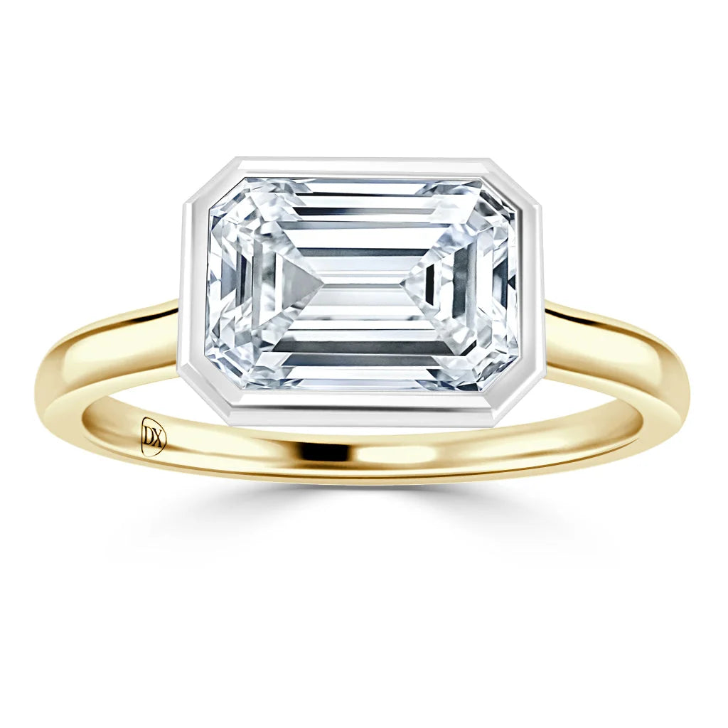 Gold band ring with a large emerald-cut diamond set in a geometric bezel setting, on a white background.