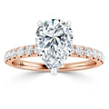 A pear-shaped diamond ring with a rose gold band, featuring round diamonds set along the band.