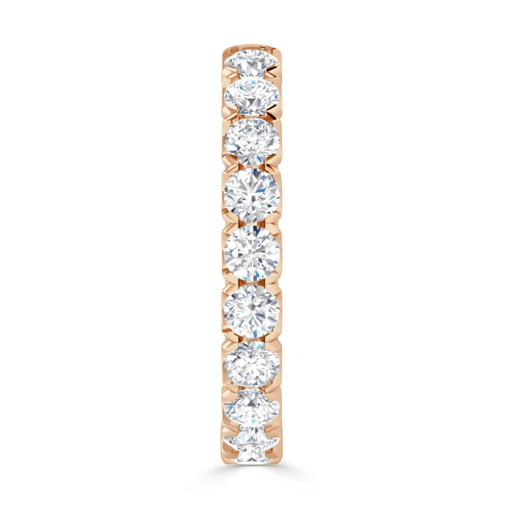 A gold ring with a vertical row of seven round, sparkling diamonds set in prongs against a white background.