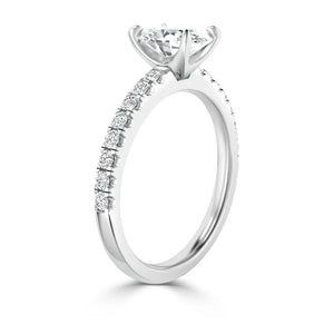 A white gold ring with a round solitaire diamond and smaller diamonds set along the band.