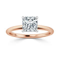 Rose gold ring with a square-cut diamond solitaire set in four prongs on a plain band.