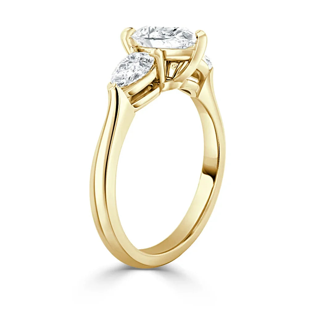 Gold ring with three oval diamonds set in prongs, viewed from an angle showing the band and side stones.