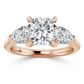 A rose gold ring with a large cushion-cut center diamond and two pear-shaped side diamonds.
