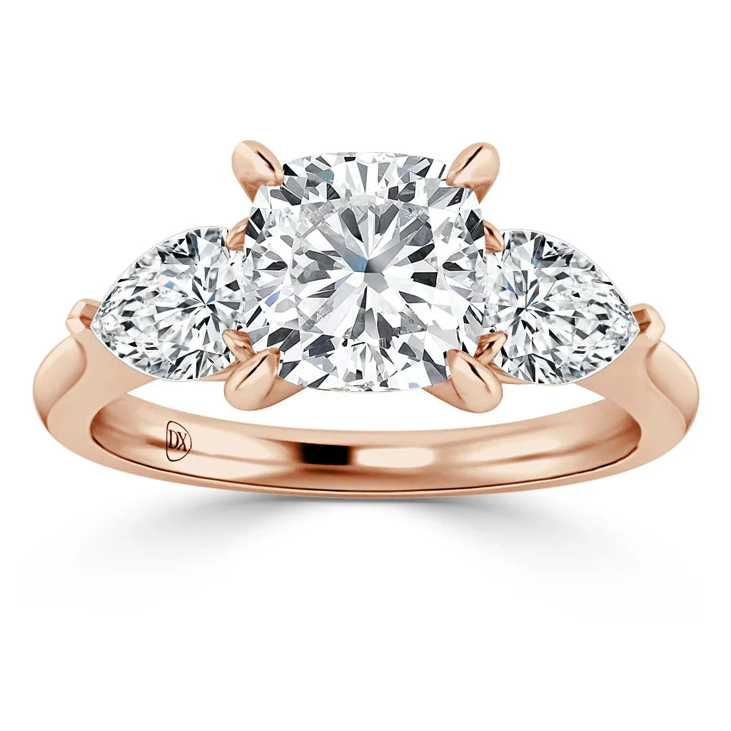 A rose gold ring with a large cushion-cut center diamond and two pear-shaped side diamonds.