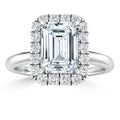 A rectangular emerald-cut diamond ring with a halo of round diamonds on a sleek silver band.