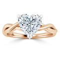 A rose gold ring with a twisted band and a large heart-shaped diamond in a prong setting.
