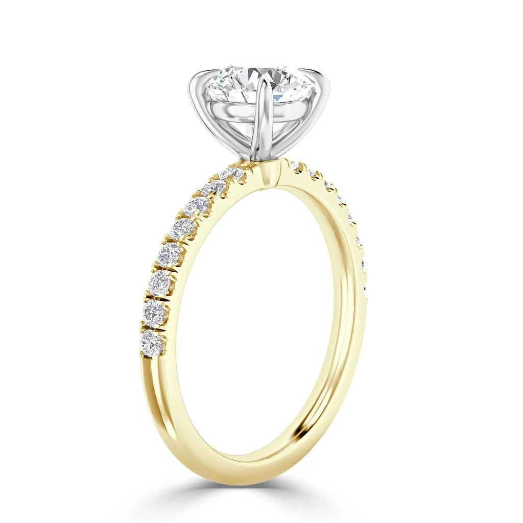Gold ring with small diamonds on the band and a large round diamond solitaire in a silver prong setting.