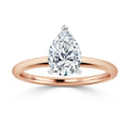 A rose gold ring with a pear-shaped diamond solitaire on a thin band, shown against a white background.