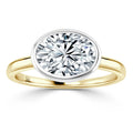 Gold band ring with a large oval-cut diamond set in a white metal bezel on a plain white background.