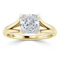 A gold ring with a large, square-cut diamond and a split shank band is shown on a white background.