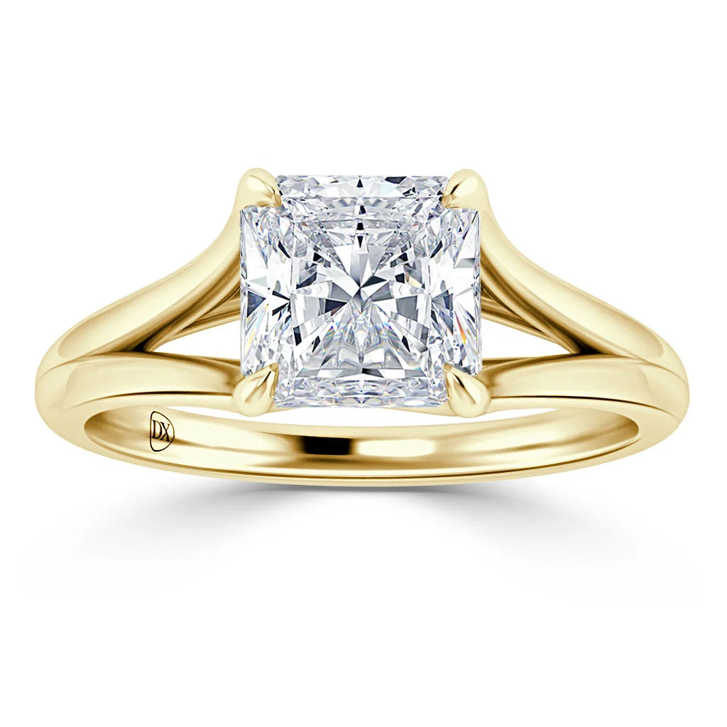 A gold ring with a large, square-cut diamond and a split shank band is shown on a white background.