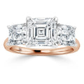 A rose gold ring with three square-cut diamonds, the center stone larger than the two side stones.