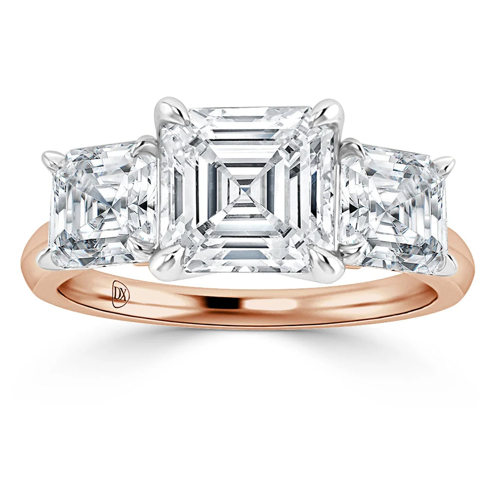 A rose gold ring with three square-cut diamonds, the center stone larger than the two side stones.