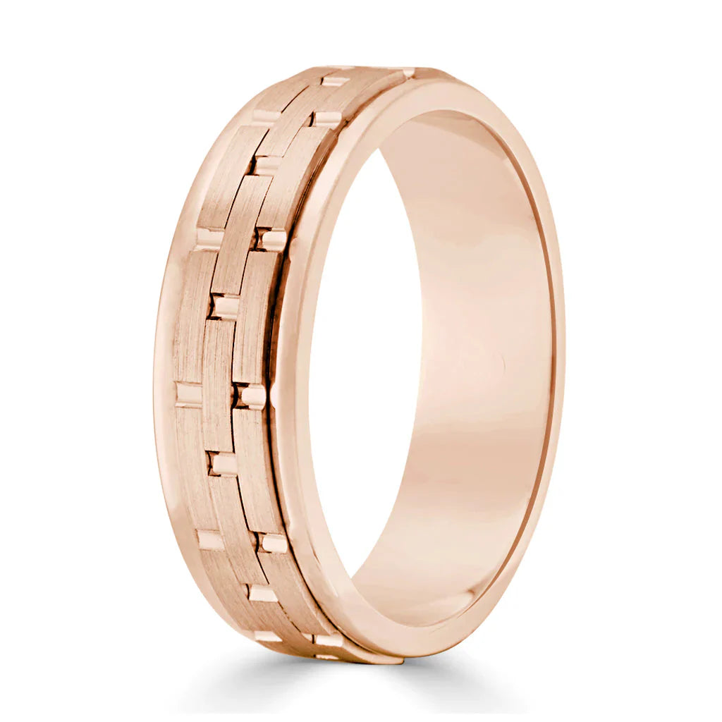 Rose gold ring with a brushed center and a geometric link pattern, polished edges, plain background.