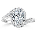 Oval diamond ring with a twisted band and halo of smaller diamonds set in white metal.