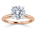 A rose gold ring with a large round diamond solitaire in a four-prong white gold setting.