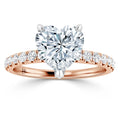 A rose gold ring with a heart-shaped diamond center stone and round diamonds set along the band.