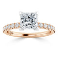 A princess-cut diamond ring with a rose gold band and small diamonds set along the band.