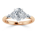 A pear-shaped diamond ring with side diamonds set on a rose gold band.