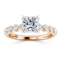 A rose gold ring with a large square center diamond and smaller round diamonds set along the band.