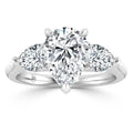A pear-shaped diamond ring with two round side diamonds set on a shiny white gold band.