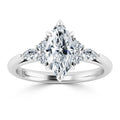 A marquise-cut diamond ring with side stones set in a polished white metal band on a white background.