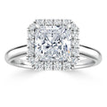 A square-cut diamond ring with a halo of smaller diamonds set on a polished silver band.