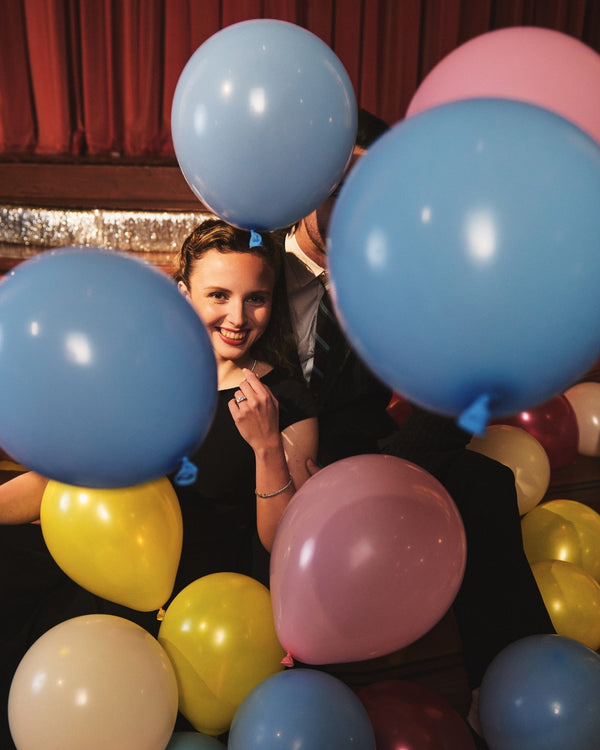 People surrounded by colorful balloons in a festive setting