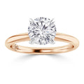 A round diamond solitaire ring with a rose gold band and white gold prongs, viewed from the front.
