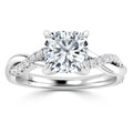 A white gold ring with a cushion-cut diamond center and a twisted band accented with small diamonds.