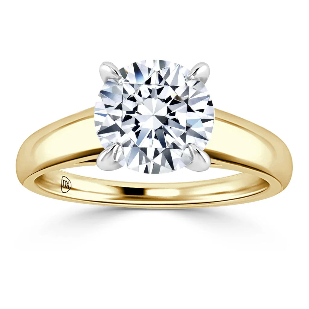 Gold band ring with a large round diamond solitaire held by four prongs, shown on a white background.