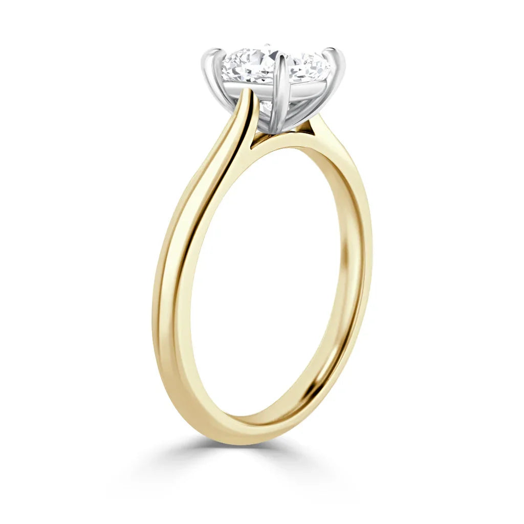 A yellow gold solitaire ring with a round, prong-set diamond in a white gold setting, shown in profile.