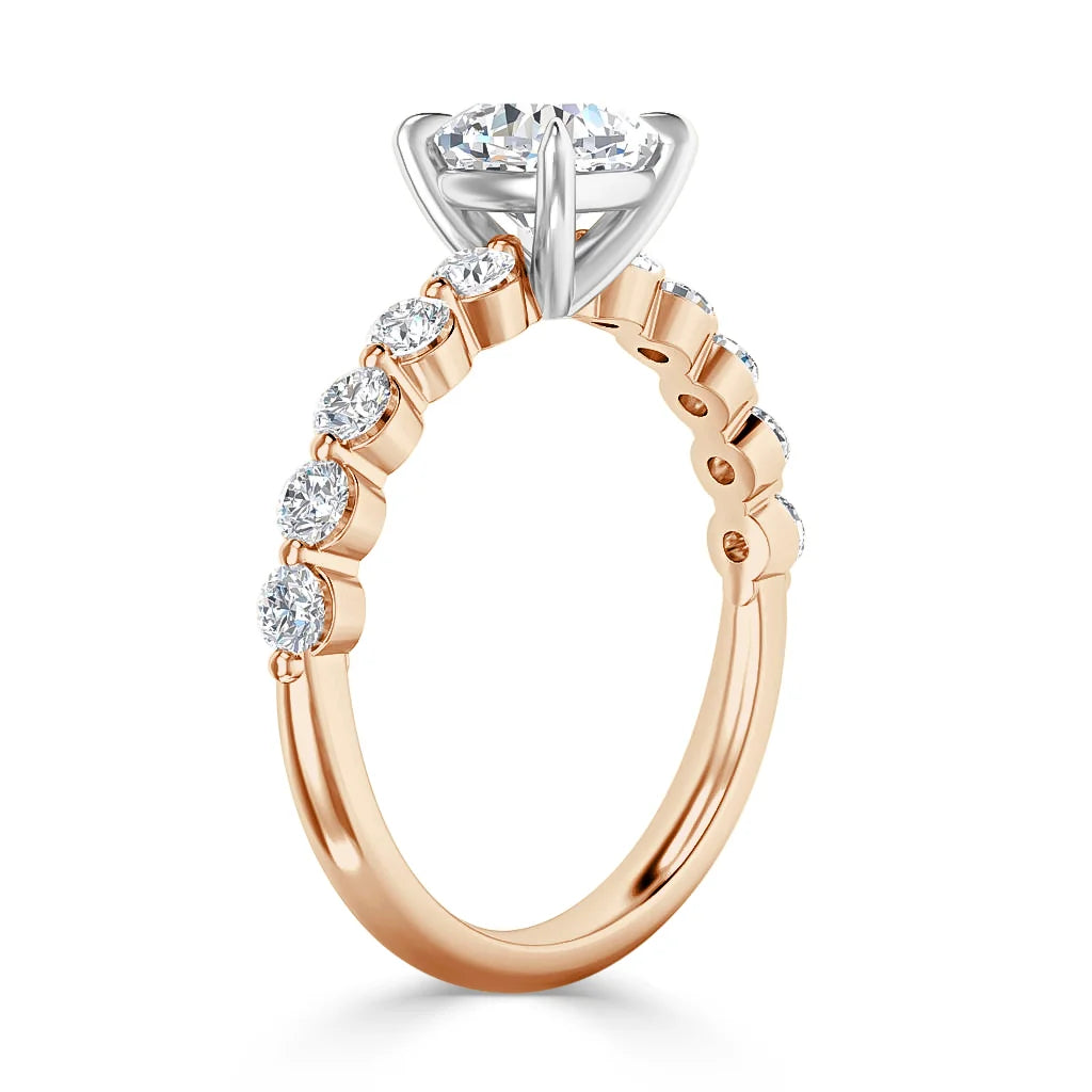 Rose gold ring with side diamonds and a large round center stone in a raised white gold prong setting.