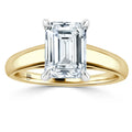 A gold band ring with a large emerald-cut diamond set in four prongs, shown on a white background.