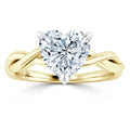 A gold ring with a twisted band and a large heart-shaped diamond in a prong setting at the center.