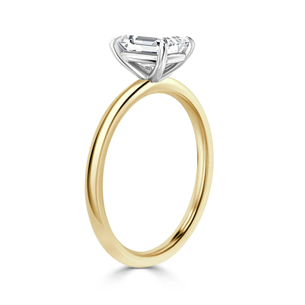 A gold ring with a thin band and a large, rectangular clear gemstone in a raised silver prong setting.