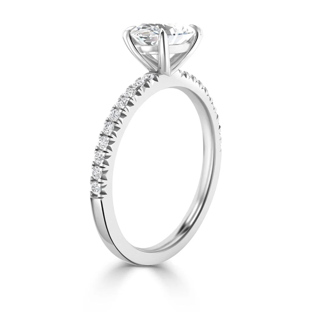 A white gold ring with a round solitaire diamond and small diamonds set along the thin band.