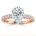 A rose gold ring with a large pear-shaped diamond center and smaller diamonds along the band.