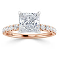A rose gold ring with a large square diamond and smaller diamonds set along the band.