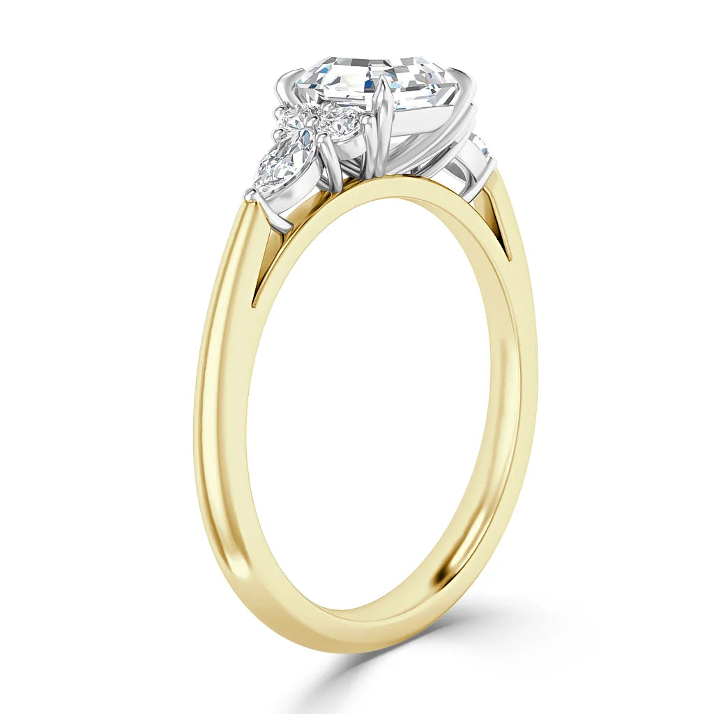 A gold band engagement ring with a large round diamond and two smaller side diamonds in a prong setting.