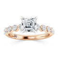 Rose gold ring with an Asscher-cut diamond center and round side diamonds on the band.