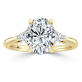 A gold ring with an oval center diamond and two triangular side diamonds set on a polished band.