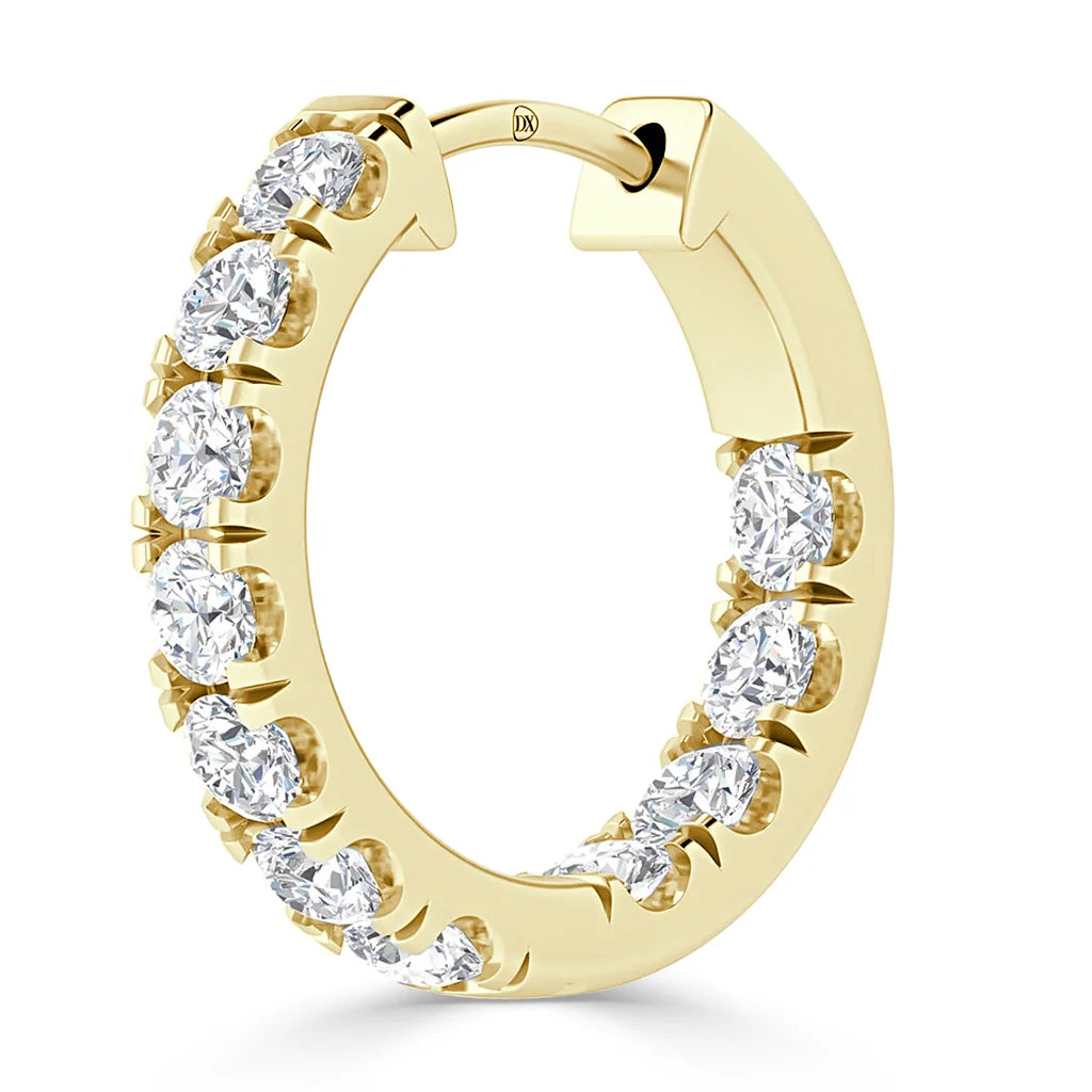 A gold hoop earring set with round white diamonds along the outer and inner edge.