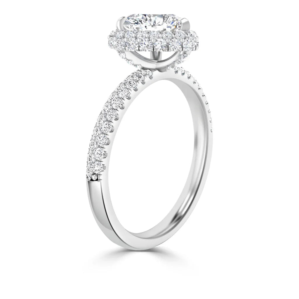 A halo diamond engagement ring with a pavé band, shown in a side view on a white background.