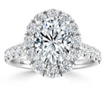 Oval diamond ring with halo and diamond-encrusted band, set in white metal, viewed from the front.