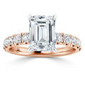 Rose gold ring with emerald-cut diamond center and round diamonds on the band, shown on a white background.